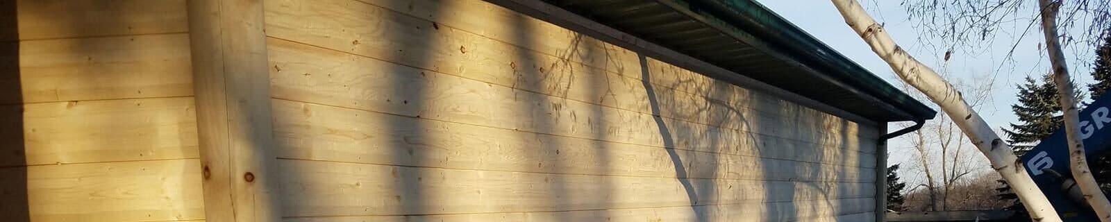 Green metal fascia and the soffit line finishing the eave above a run of fresh natural-wood lap siding.