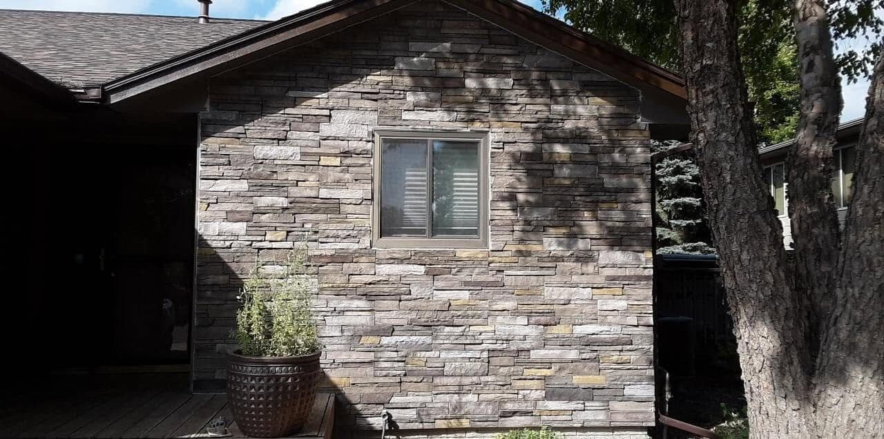 A gable wall clad in stacked-stone veneer around a picture window.