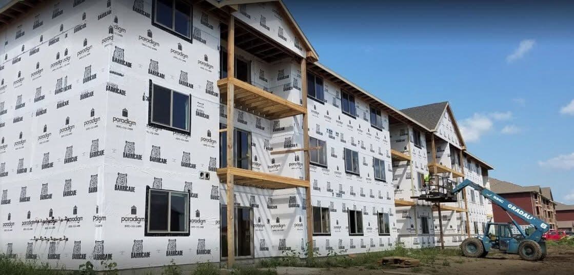A multi-story jobsite wrapped in weather-resistant house-wrap with new windows, before the new siding goes on.